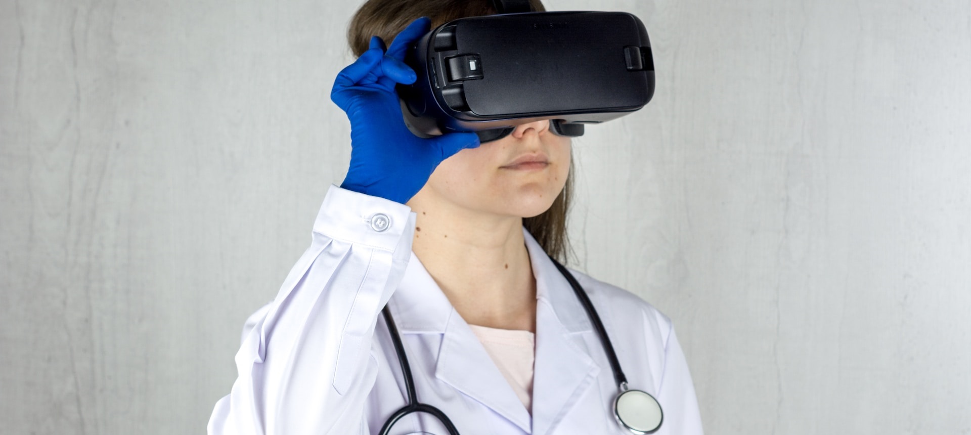 Woman in lab coat with a stethoscope around her neck using a VR headset.