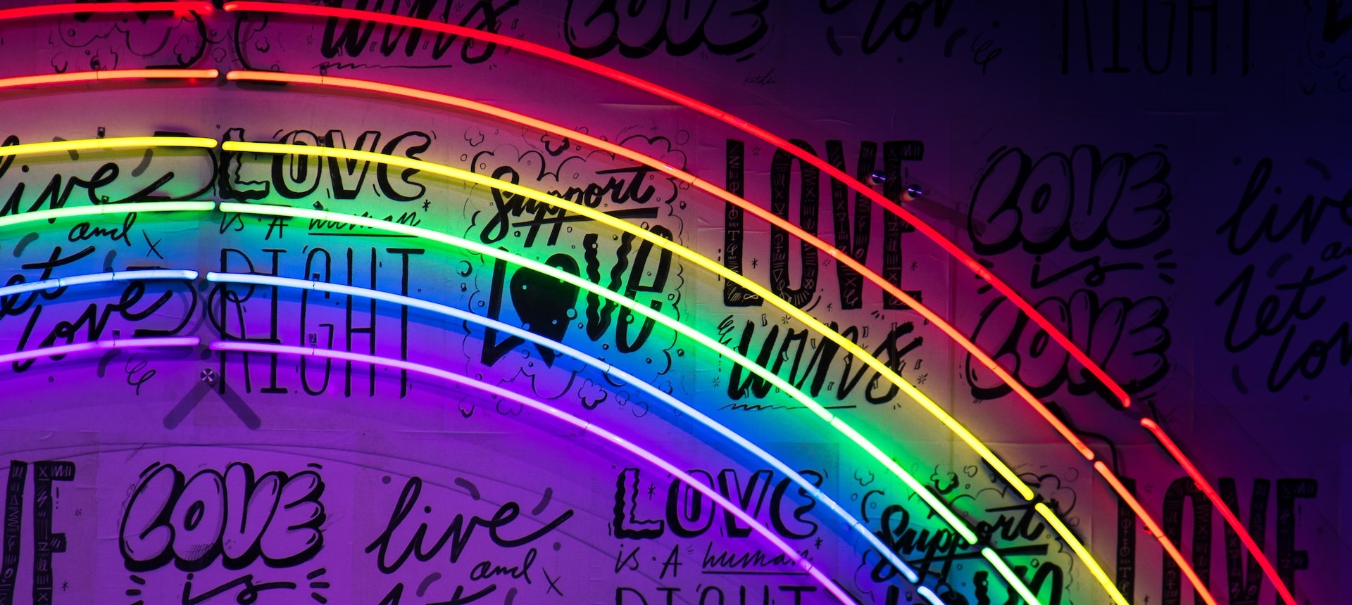 Neon rainbow with love messages for Pride Month. Photo by Jason Leung on Unsplash